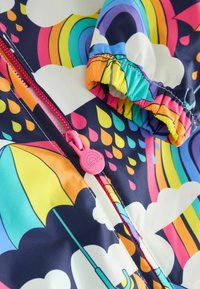 Colorful waterproof jacket featuring a rainbow and cloud pattern. Includes a pink zipper and elastic cuffs for a snug fit.
