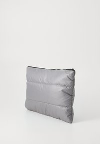 Harmaa pehmustettu clutch-tasku, jossa on vetoketjukiinnitys, suorakaiteen muotoinen, sileä pinta ja vaakasuunnassa ommellut osat lisäyksinä.