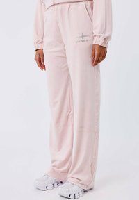 Lichtroze sweatpants gemaakt van zachte stof. Voorzien van een elastische tailleband en zijzakken. Inclusief een zilveren ster ontwerp op de linkerdij.