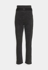 Pantalon en denim noir à coupe droite, avec un tissu texturé, une taille élastique et des détails de couture minimalistes.