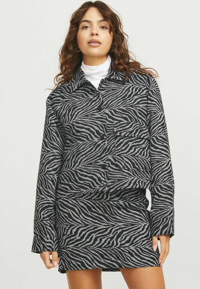 Juostelės rašto marškiniai ir sijonas, juodos ir pilkos spalvos, su apykakle, mygtukų užtrauktuku ir ilgomis rankovėmis. Minkšta tekstūra.