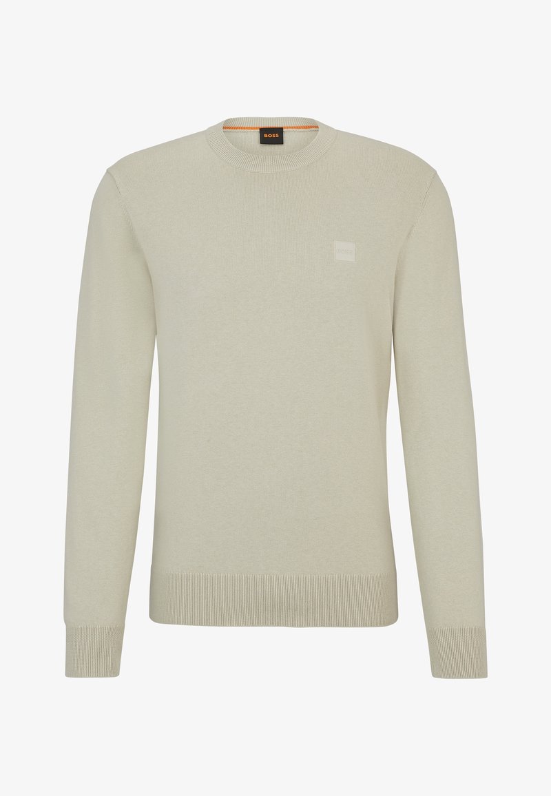 Pull beige à manches longues avec col rond, poignets et ourlet côtelés, avec un petit patch logo embossé sur la poitrine.