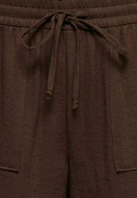 Pantalon marron texturé avec taille élastique et cordon noué, doté de poches plaquées à l'avant et de coutures verticales visibles.