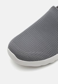 Gray woven textile slip-on shoe with a rounded toe and white rubber sole. Features a textured upper for breathability and comfort.