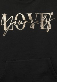Svart sweatshirt med metallisk guldtext som läser "ÄLSKA dig själv" i en blandning av fet och kursiv stil; inkluderar en frampocket.