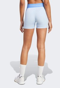 Pantaloni corti sportivi di un blu chiaro con una vita a contrasto blu, che mostrano un design elegante e aderente e una superficie liscia.