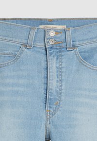 Vaqueros ajustados de talle alto en denim azul claro. Presentan un cierre de doble botón, costuras en contraste de color naranja y una textura suave.