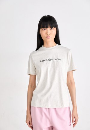Grå t-skjorte med kort erme og "Calvin Klein Jeans" trykt i svart. Stoffet er mykt, lett og har en klassisk rund hals-design.