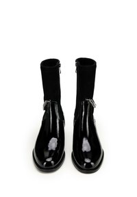 Czarne lakierowane botki za kostkę z dopasowanym, miękkim czarnym materiałem na górze, posiadające zamek błyskawiczny po boku i dekoracyjne srebrne akcenty.