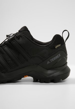 Black Adidas Terrex hiking shoe with Gore-Tex label, rugged sole, and quick-lace system, shown from the side on a plain background.