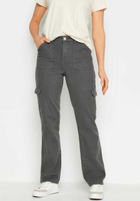 Grijze cargo-broeken met een ontspannen pasvorm, voorzien van voor- en zijzakken, een knoopsluiting en witte stiksels. Gecombineerd met een beige top.