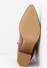 Chaussure à bout pointu en cuir terracotta, avec une finition lisse, dotée d'un talon texturé et d'une semelle en caoutchouc légère. La taille 37 est visible.