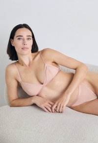 Růžový žebrovaný bikini set s trojúhelníkovým vrškem a odpovídajícími spodními díly. Obsahuje tenké ramínka a vykrojené okraje. Měkká, strukturovaná tkanina.