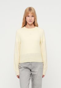 Ανοιχτό κίτρινο, πλεκτό πουλόβερ με μαλακή υφή, στρογγυλή λαιμόκοψη και μακριά μανίκια, με διακριτική διαβάθμιση στο τελείωμα.