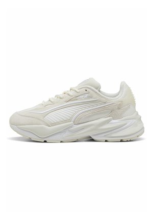 Baskets de sport couleur crème avec empiècements en mesh texturé et en suède, semelle épaisse sculptée et fermeture à lacets, vue de côté.