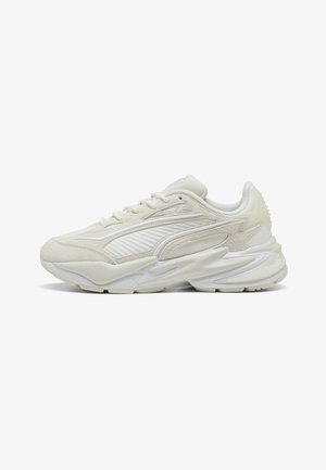 Baskets de sport couleur crème avec empiècements en mesh texturé et en suède, semelle épaisse sculptée et fermeture à lacets, vue de côté.