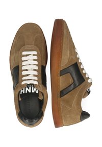 Sneaker in suede marrone con accenti in pelle nera, lacci bianchi e suola in gomma. Presentano una punta arrotondata e un dettaglio del logo laterale a contrasto.