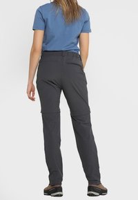 Kvinnors gråa zip-off vandringsbyxor i lätt material, med en avslappnad passform, fickor och justerbar midja, tillsammans med en blåtröja.