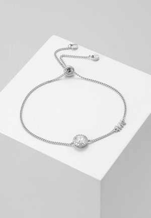 Bracelet chaîne réglable en argent avec une pierre précieuse ronde et claire centrale et un charme "M" sur une plateforme blanche.