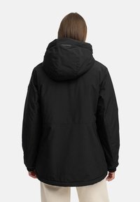 Giacca isolante nera con un grande cappuccio, tasche con cerniera e una vestibilità rilassata. Caratterizzata da una texture liscia e un design minimalista.