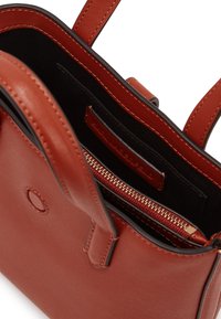Brown leather handbag with multiple compartments. Features a zippered pocket and a smooth texture. Interior lined with black fabric.
