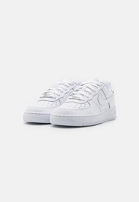 Hvite skinn sneakers med perforert tåboks, polstret tunge, flate lisser og strukturert gummisåle. Har en swoosh-logo på siden.