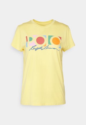 Żółta koszulka z krótkim rękawem z wielokolorowym geometrycznym napisem "POLO" oraz niebieskim kursywowym napisem "Ralph Lauren" na przodzie.