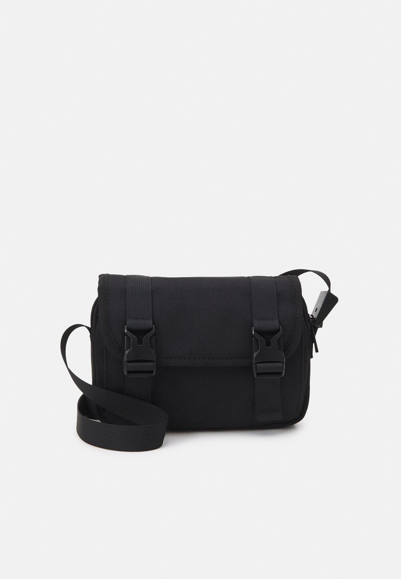 Black messenger bag made of fabric with a textured surface. Features two adjustable buckle closures and a detachable shoulder strap.