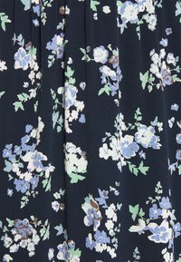 Tissu floral en bleu marine avec des fleurs bleu clair, blanches et vertes, agrémentées de touches de brun ; surface texturée avec un tomber doux et des plis.
