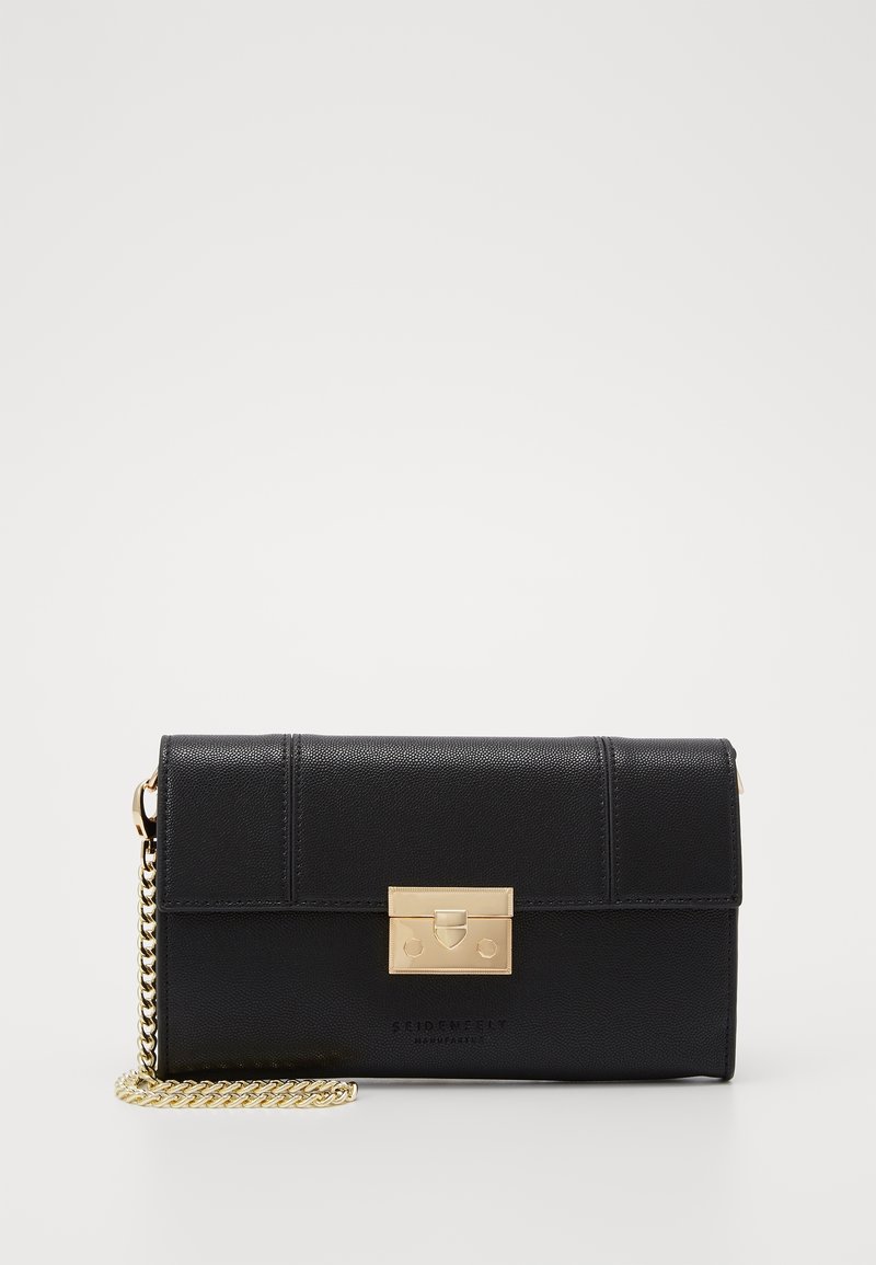 Pochette rectangulaire noire avec une bandoulière chaîne dorée et un fermoir métallique doré sur un fond blanc uni.