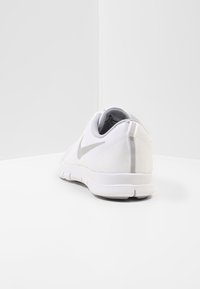 Hvid Nike løbesko med grå swoosh, åndbart mesh-overdel og fleksibel sål, vist fra bag- og sidevinkel på hvid overflade.