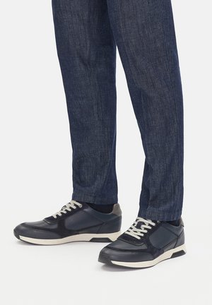 Zapatillas con una mezcla de cuero azul marino y ante, detalles blancos y cordones gris claro. Presentan un perfil bajo y paneles texturizados.