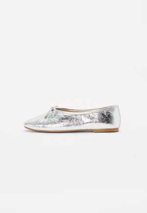 Ballerines argentées avec une finition métallique, présentant un bout arrondi et un nœud décoratif à l'avant. Semelle plate, design minimal.