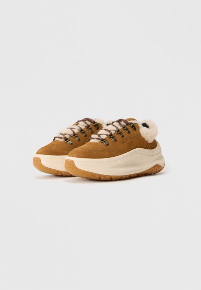Brune ruskinds sneakers med pelsfor, tykke hvide såler, brune snørebånd og "MOON BOOT" præget på siden.