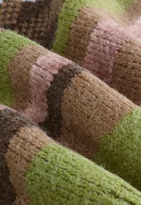 Knit textile with brown, green, and pink stripes. The texture is fuzzy with varied thickness, creating a tactile, woven appearance.