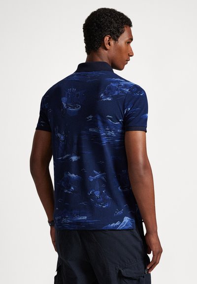 Tamsiai mėlynas polo marškinėlis su raštuotu dizainu, vaizduojančiu laivus ir kalnus, trumpomis rankovėmis ir klasikine apykakle. Lygus tekstūra.