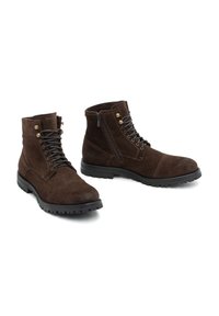 Stivaletti alla caviglia in suede marrone con punta rotonda, lacci frontali, chiusura con zip e suole in gomma nera testurizzata. Occhielli in metallo e dettagli con logo visibili.