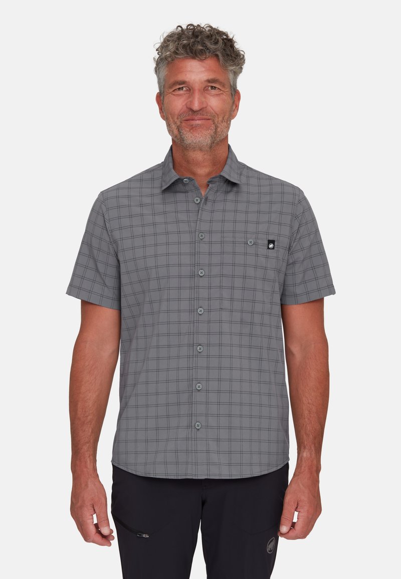 Camicia a maniche corte, con bottoni, di colore grigio con un motivo a griglia nera e una tasca sul petto. Realizzata in un tessuto leggero e liscio.