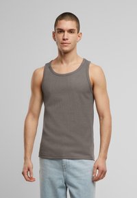 Grå stripete tank topp med rund hals, ermeløs design og tettsittende snitt, kombinert med lyseblå jeans.