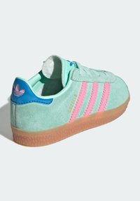 Semišová teniska v mentolově zelené barvě s růžovými pruhy, zaoblenou špičkou a světle hnědou gumovou podrážkou. Obsahuje modré akcenty a značku "Gazelle".