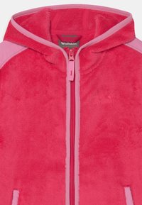 Fleecejacka i livlig rosa med dragkedja fram, kontrasterande rosa detaljer på axlarna och broderad logotyp på bröstet. Mjuk textur.