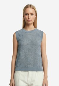 Ärmlös ljusblå tröja med ett texturerat geometriskt mönster, ribbad krage och fåll, tillverkad av ett mjukt stickat tyg.