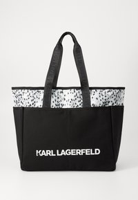 Svart totebag med et mønstret grått toppbånd og teksturerte svarte sider, med doble svarte håndtak og hvit "KARL LAGERFELD" merkevare.