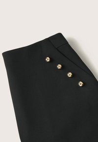 Tessuto nero con una trama liscia, caratterizzato da quattro bottoni dorati lucidi disposti in fila lungo il bordo. Design semplice e minimalista.