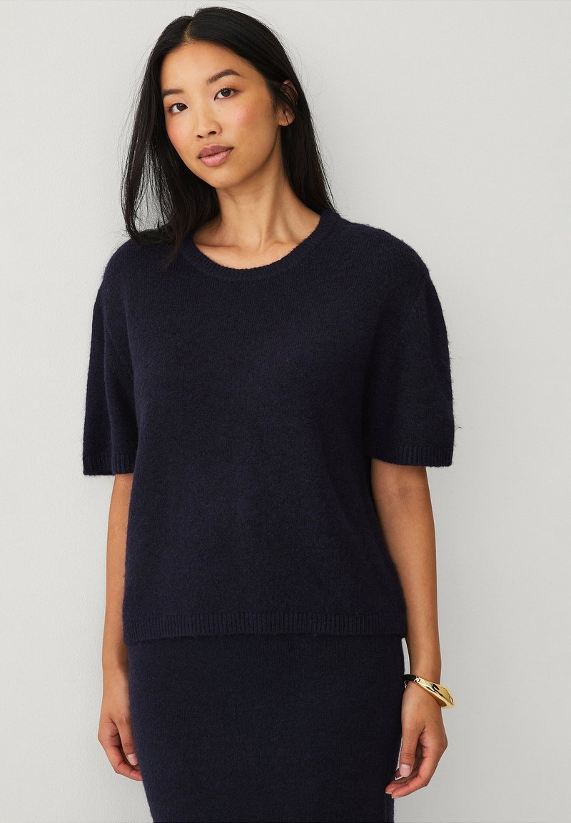 Marineblå uldblanded kortærmet sweater med rund halsudskæring og ribbet manchetter. Blød tekstur og en afslappet pasform. Simpelt design uden synlige mønstre.
