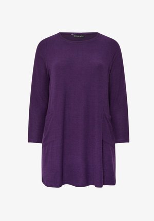 Fioletowa tunika z okrągłym dekoltem, rękawami o długości trzech czwartek i dwoma przednimi kieszeniami. Wykonana z miękkiego materiału o lekko strukturalnym wykończeniu.