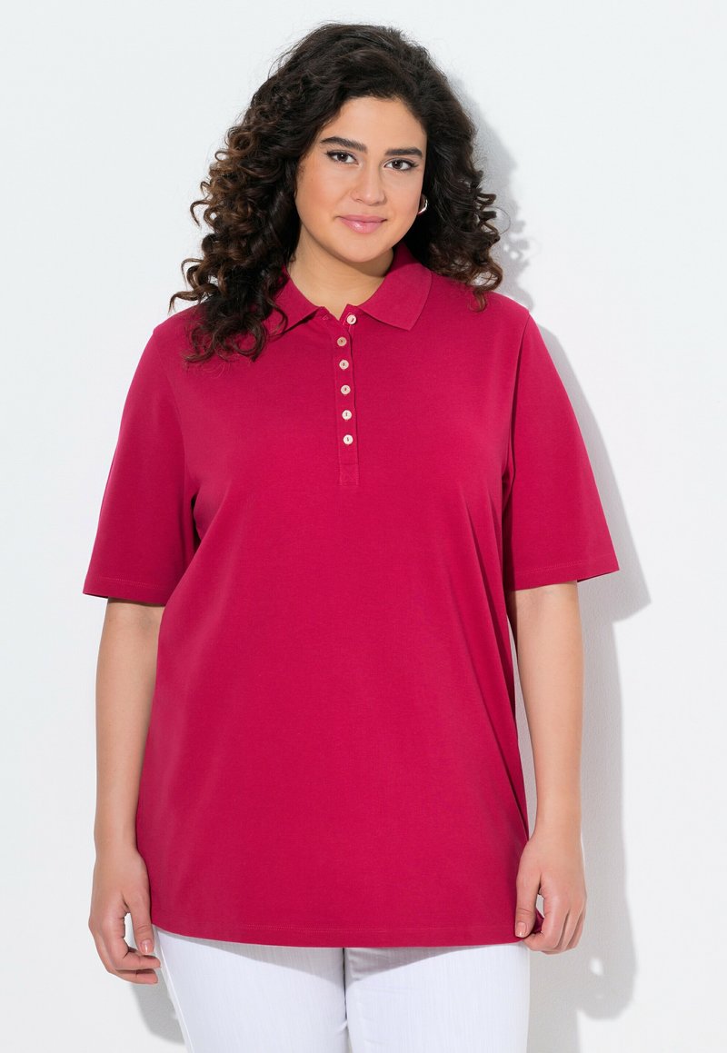 Polo a maniche corte in fucsia con patta di bottoni e colletto; realizzato in cotone; texture liscia; vestibilità comoda, indossato con pantaloni bianchi.