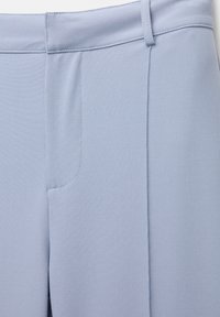 Pantalon bleu clair sur mesure avec passants pour ceinture, poche avant et une texture de tissu propre et lisse.