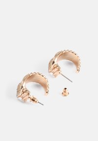 Guldtonade hoops med en snurrad design, prydda med klara cubic zirconia-accenter och metallstift för säker fastsättning. Tre komponenter ingår.