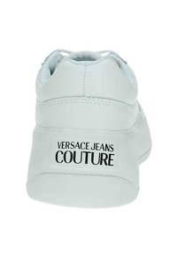 Sneaker bianca con parte superiore in pelle liscia, tallone testurizzato e logo "VERSACE JEANS COUTURE" in bold nero sul retro.